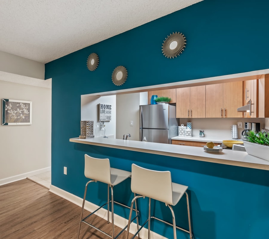 Modern kitchen with pass-through and breakfast bar seating at Meadow Walk Apartments in Miami Lakes, Florida