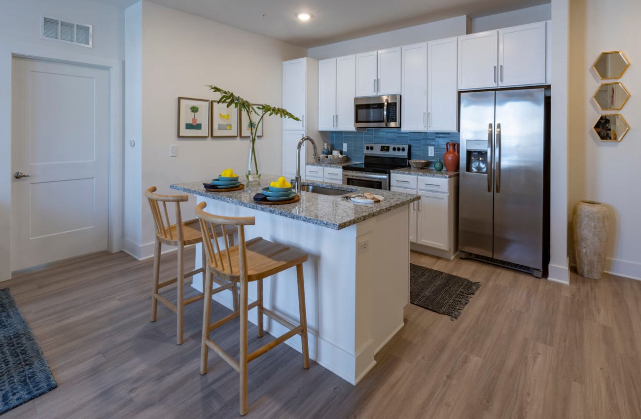 1 BR Apartments in Ponte Vedra Beach, FL - Cadence at Nocatee - Kitchen with Stainless Steel Appliances, White Cabinetry, Granite Countertops, and Vinyl Plank Flooring.