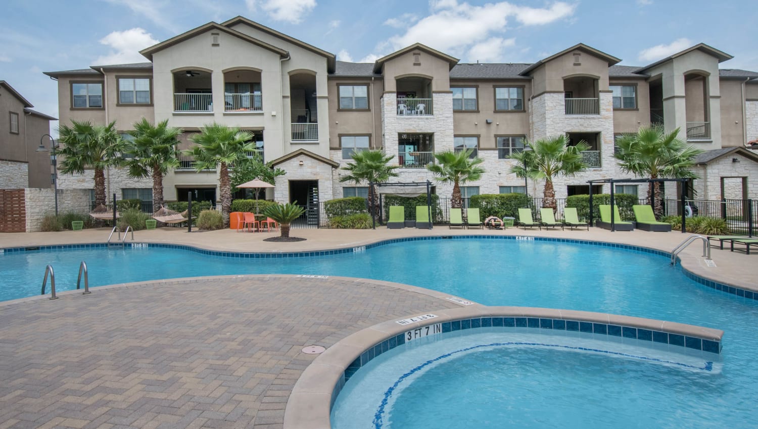 Resort-style swimming pool surrounded by palm trees at Carrington Oaks in Buda, Texas