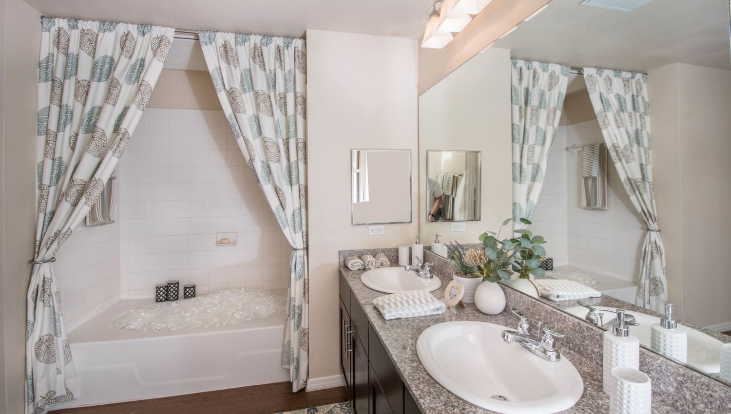 Primary bathroom with an oval tub and two sinks in a model apartment at Carrington Oaks in Buda, Texas