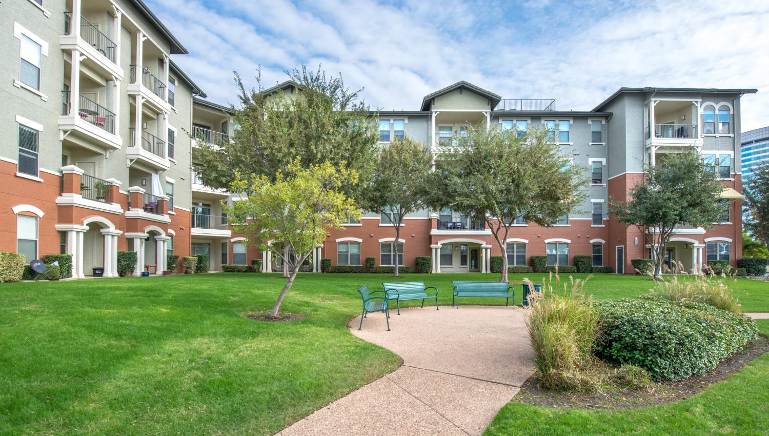 Mature trees and well-manicured landscaping outside resident buildings at Olympus Las Colinas in Irving, Texasq