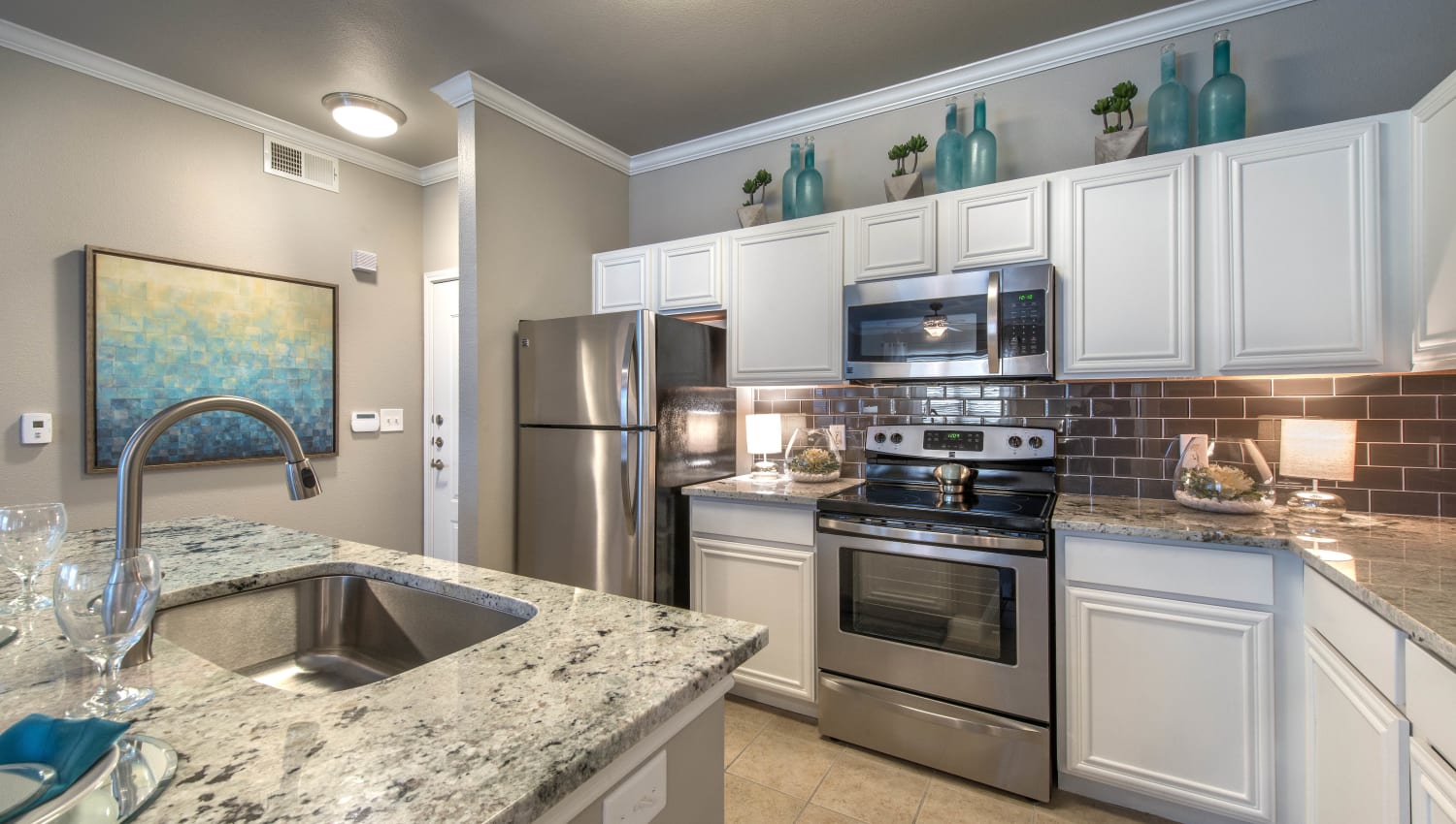 Stainless-steel appliances and white cabinetry in a model apartment's kitchen at Olympus Las Colinas in Irving, Texas