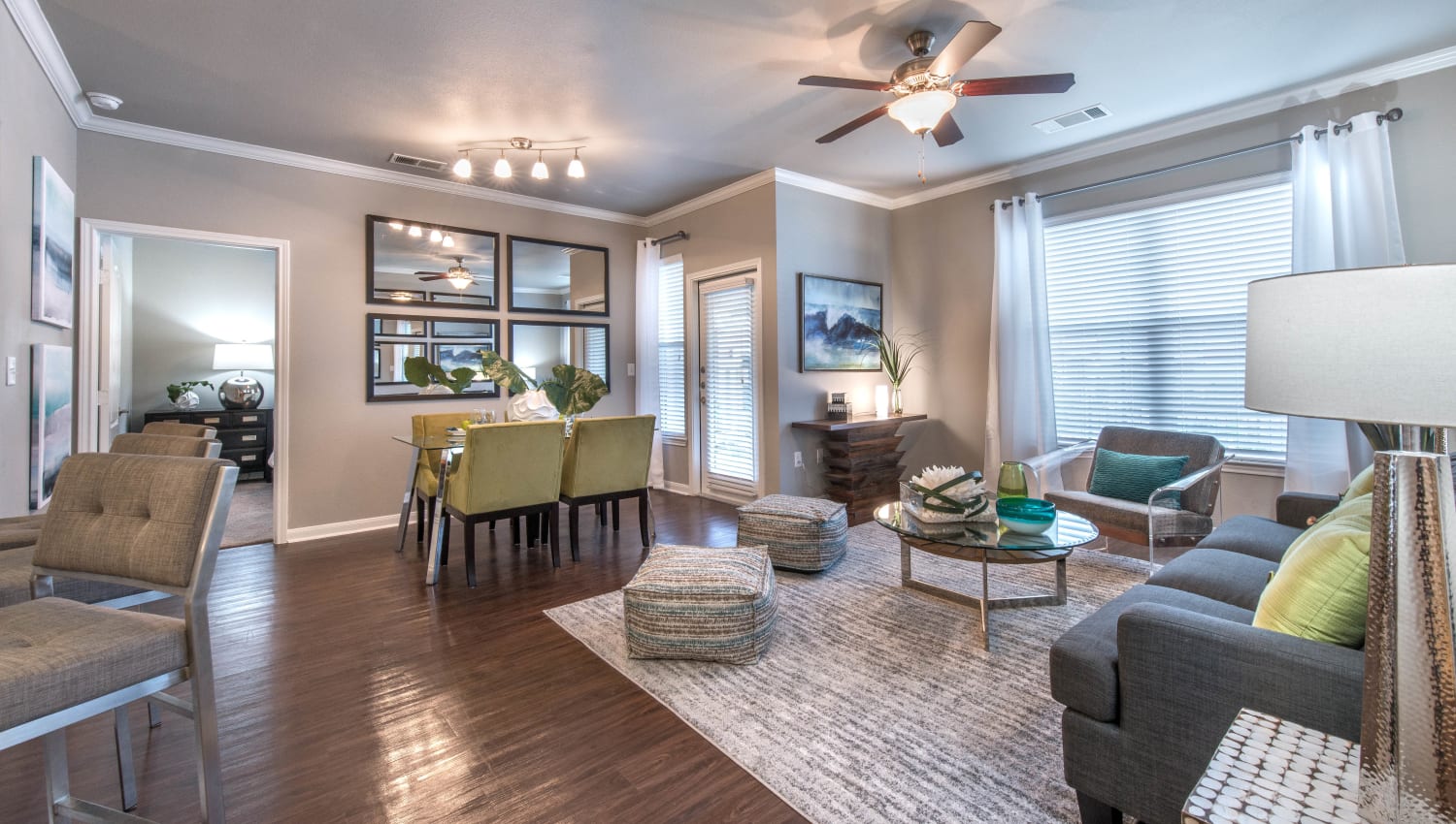 Bay windows and a ceiling fan in the living area of a model home at Olympus Las Colinas in Irving, Texas