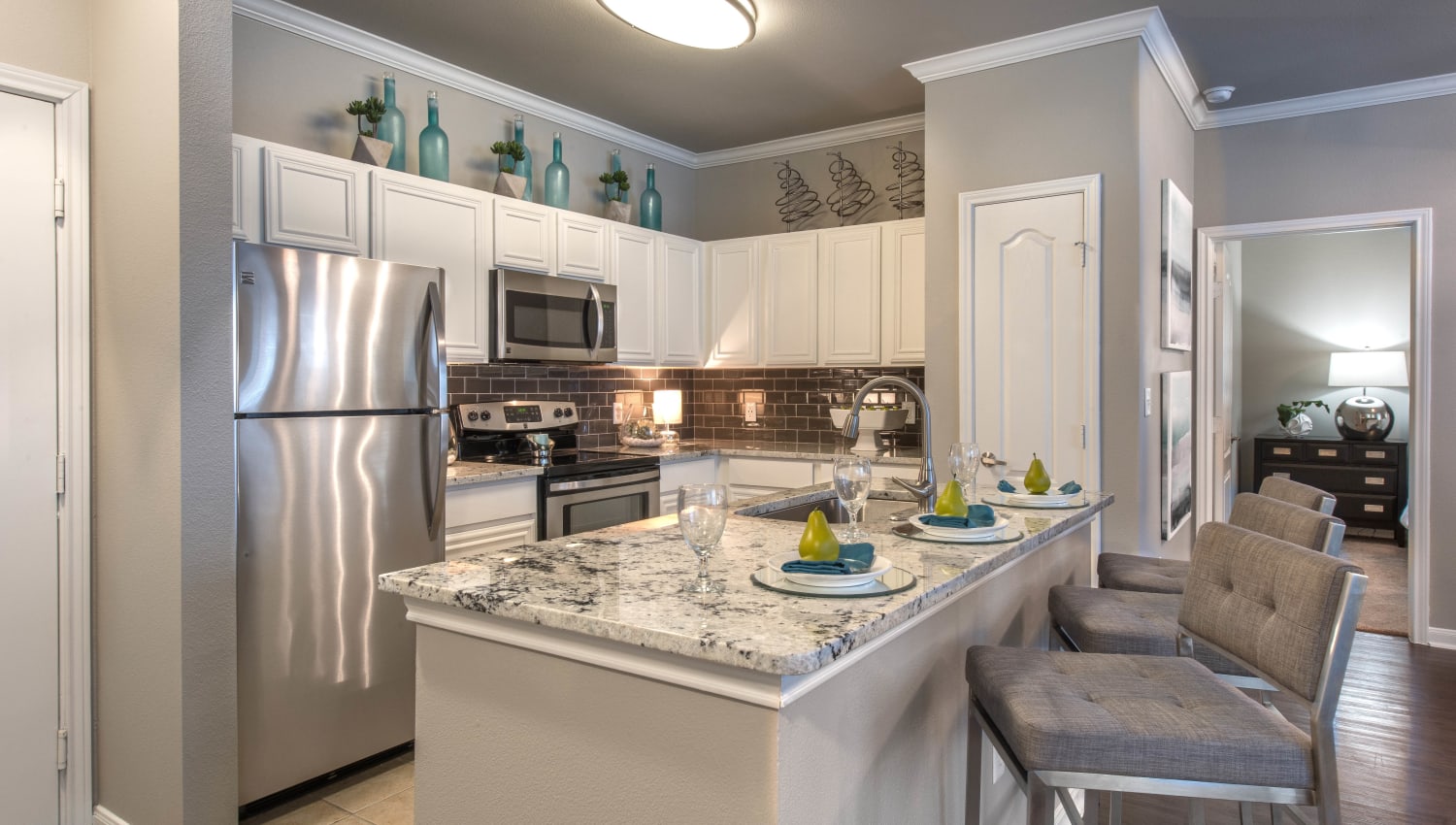 Gourmet kitchen with an island and breakfast bar in a model apartment at Olympus Las Colinas in Irving, Texas