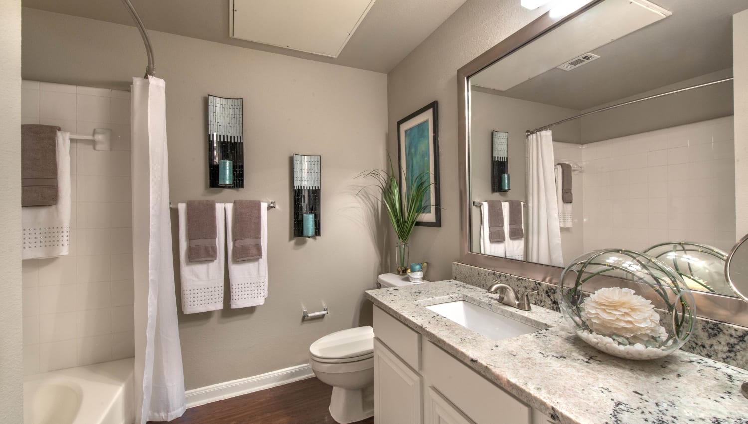 Master bathroom with a tiled shower and hardwood flooring in a model home at Olympus Las Colinas in Irving, Texas