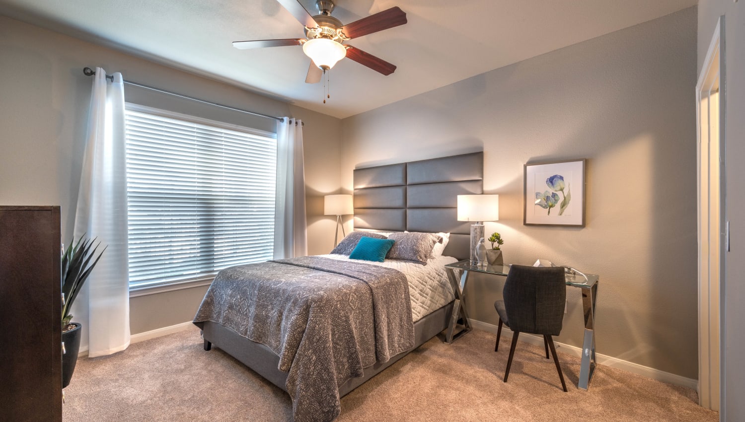Plush carpeting and bay windows in the primary bedroom of model apartment home at Olympus Las Colinas in Irving, Texas