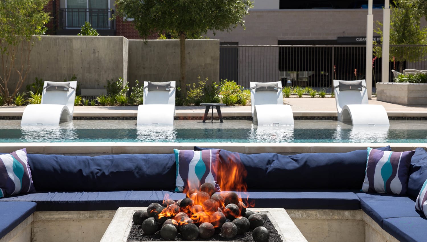 Lounge seating around the fire pit near the pool at Lux on Main in Carrollton, Texas