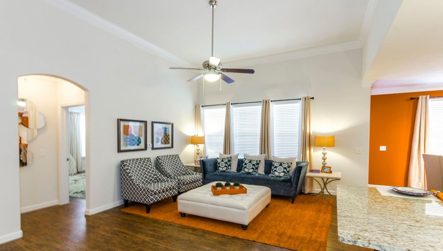 Well-furnished living area with a ceiling fan in a model home at Olympus Woodbridge in Sachse, Texas