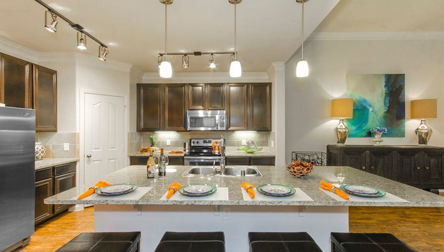 Model home's kitchen with an island and granite countertops at Olympus Woodbridge in Sachse, Texas