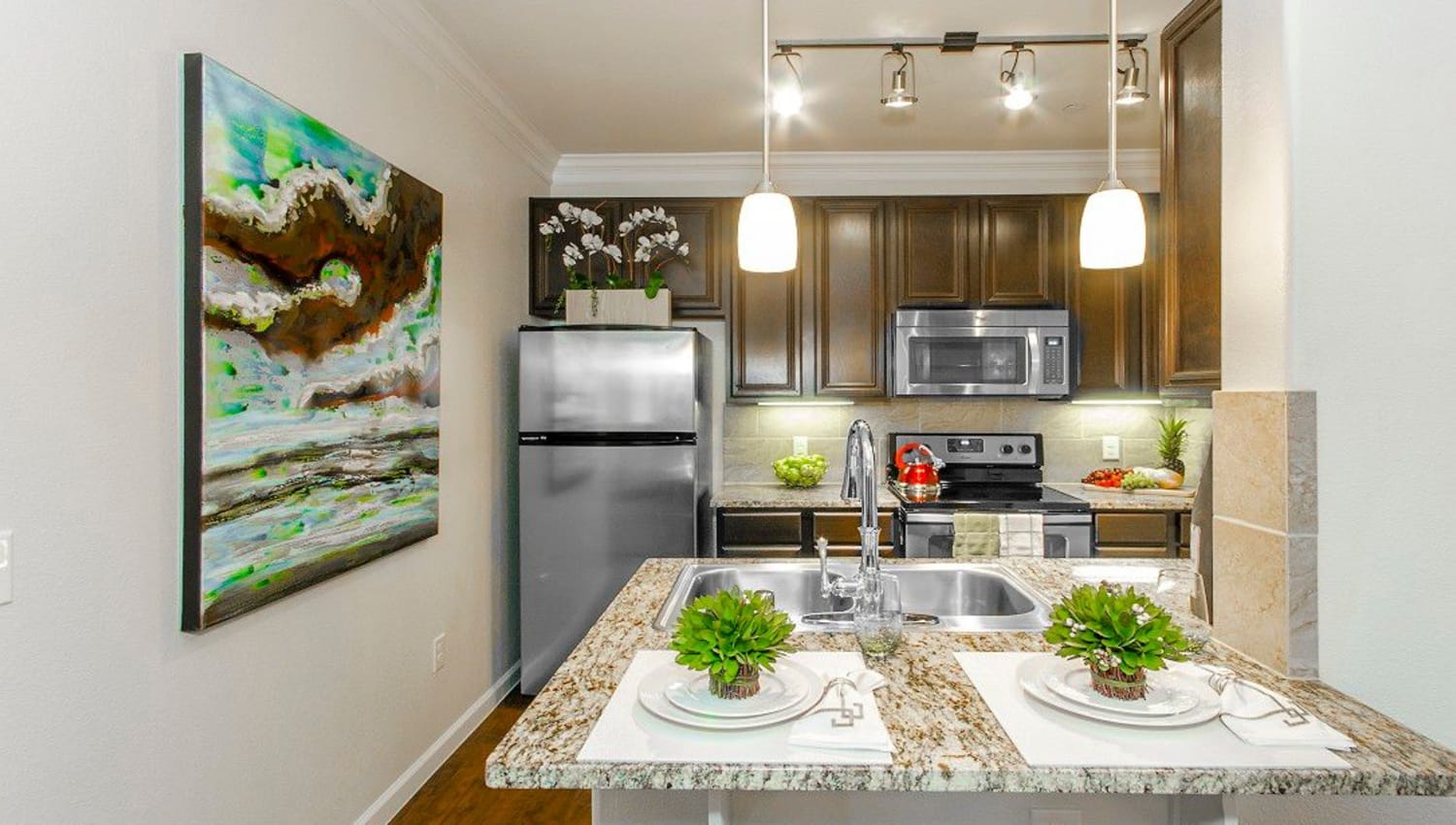 Stainless-steel appliances and custom lighting in a model home's kitchen at Olympus Woodbridge in Sachse, Texas