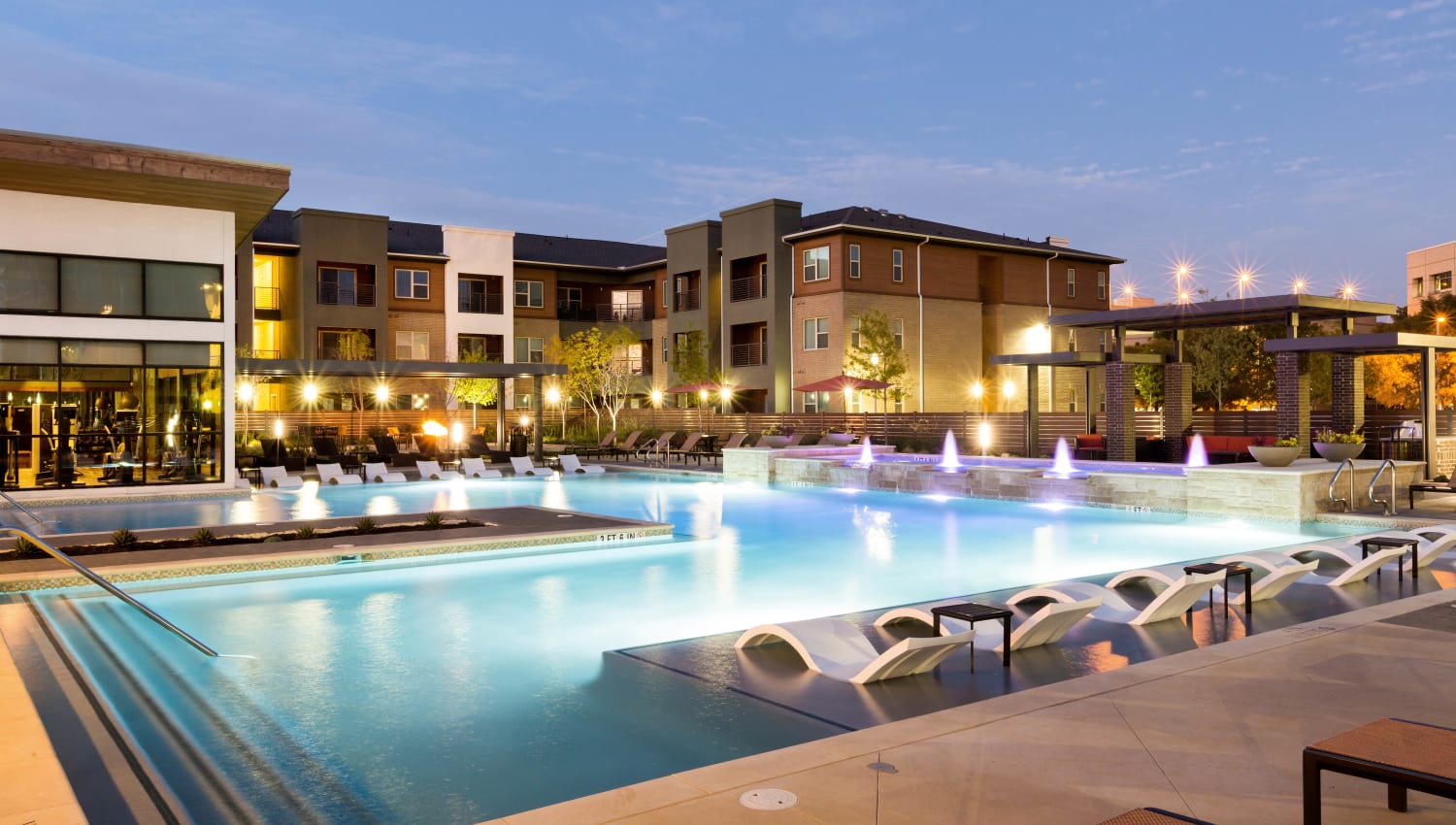 Vibrantly illuminated swimming pool at twilight at The Davis in Fort Worth, Texas