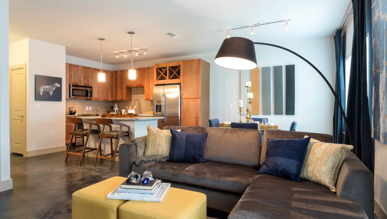 Well-furnished living area with the kitchen in the background of a model apartment at The Davis in Fort Worth, Texas