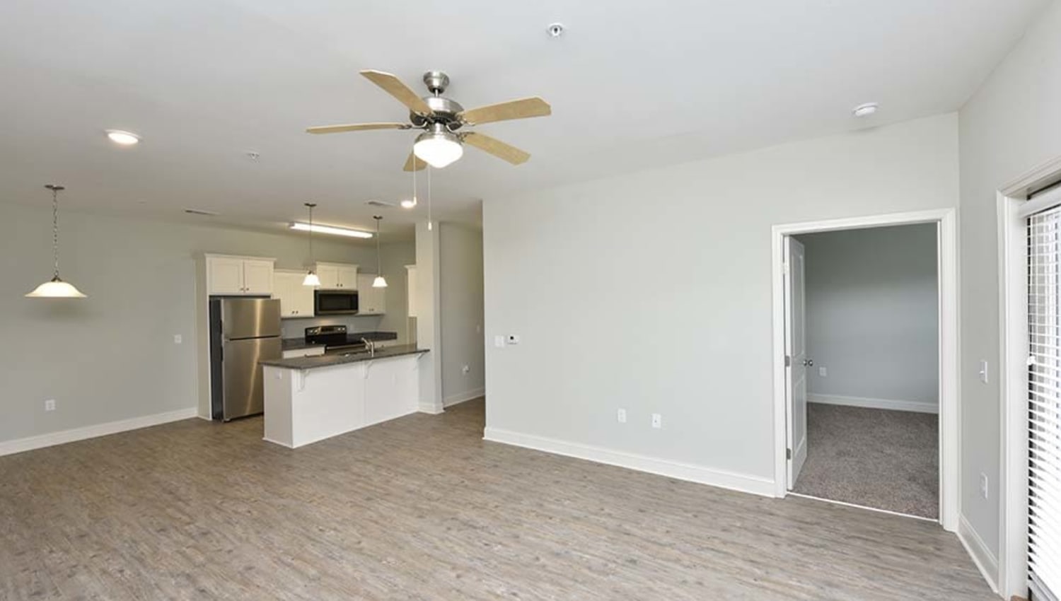 Roomy open-concept floor plan with a ceiling fan in a model apartment at The Enclave in Brunswick, Georgia