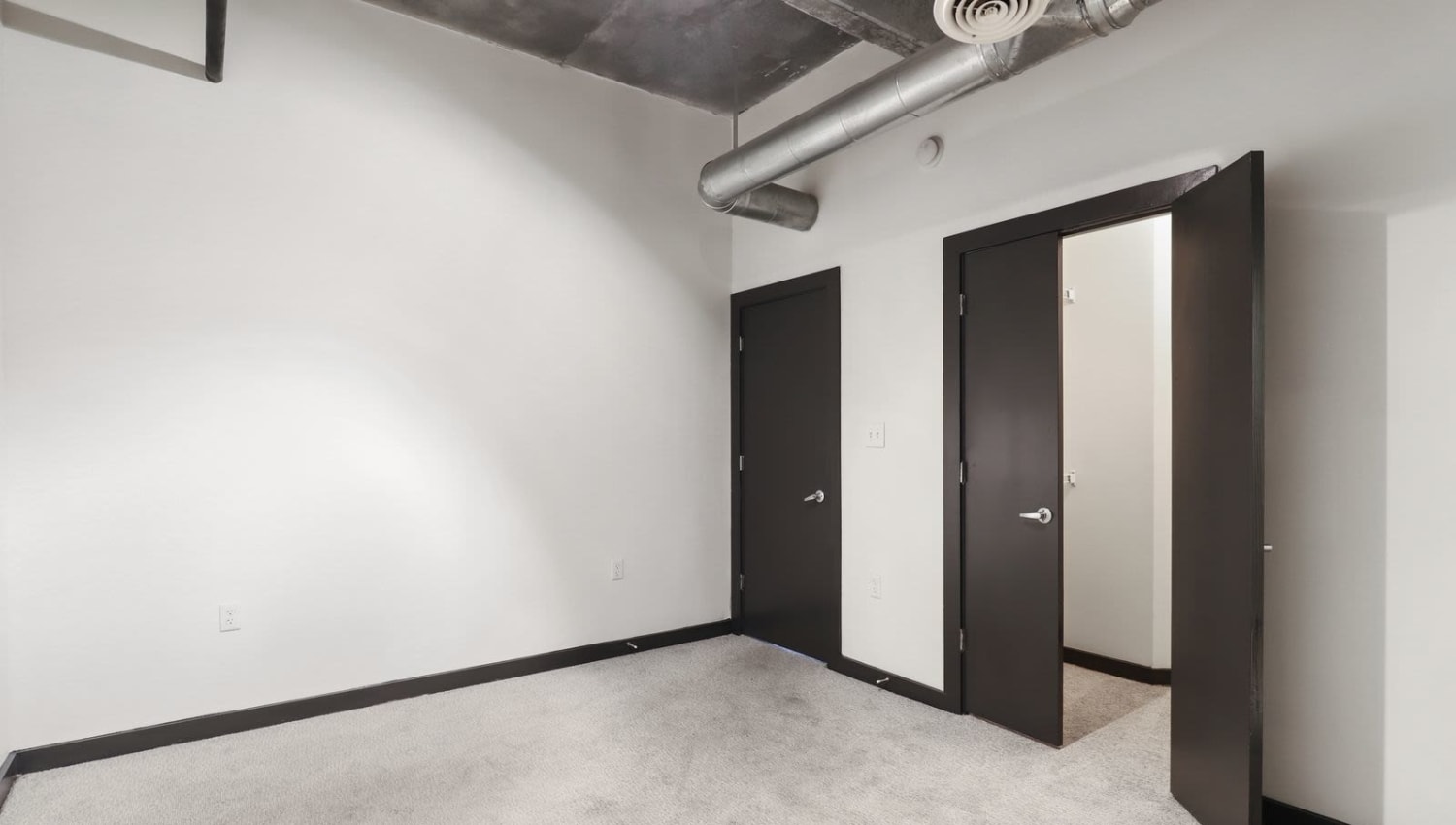 Carpeted bedroom with industrial look at 17th Street Lofts in Atlanta, Georgia