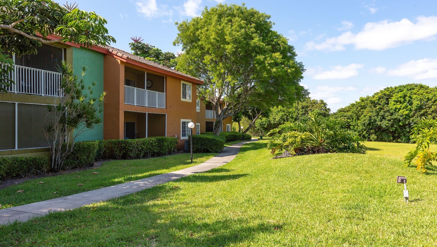 Exterior view of apartment buildings and lawn at Whalers Cove Apartments in Boynton Beach, Florida