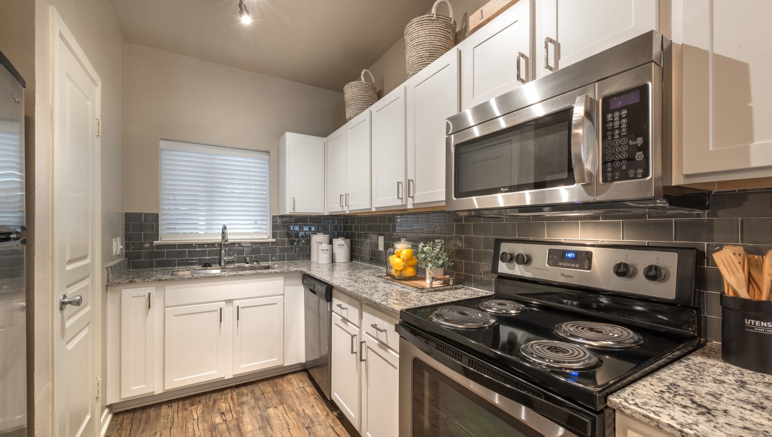 Fully equipped kitchen with granite countertops and subway tile backsplash at 75 West in Dallas, Texas