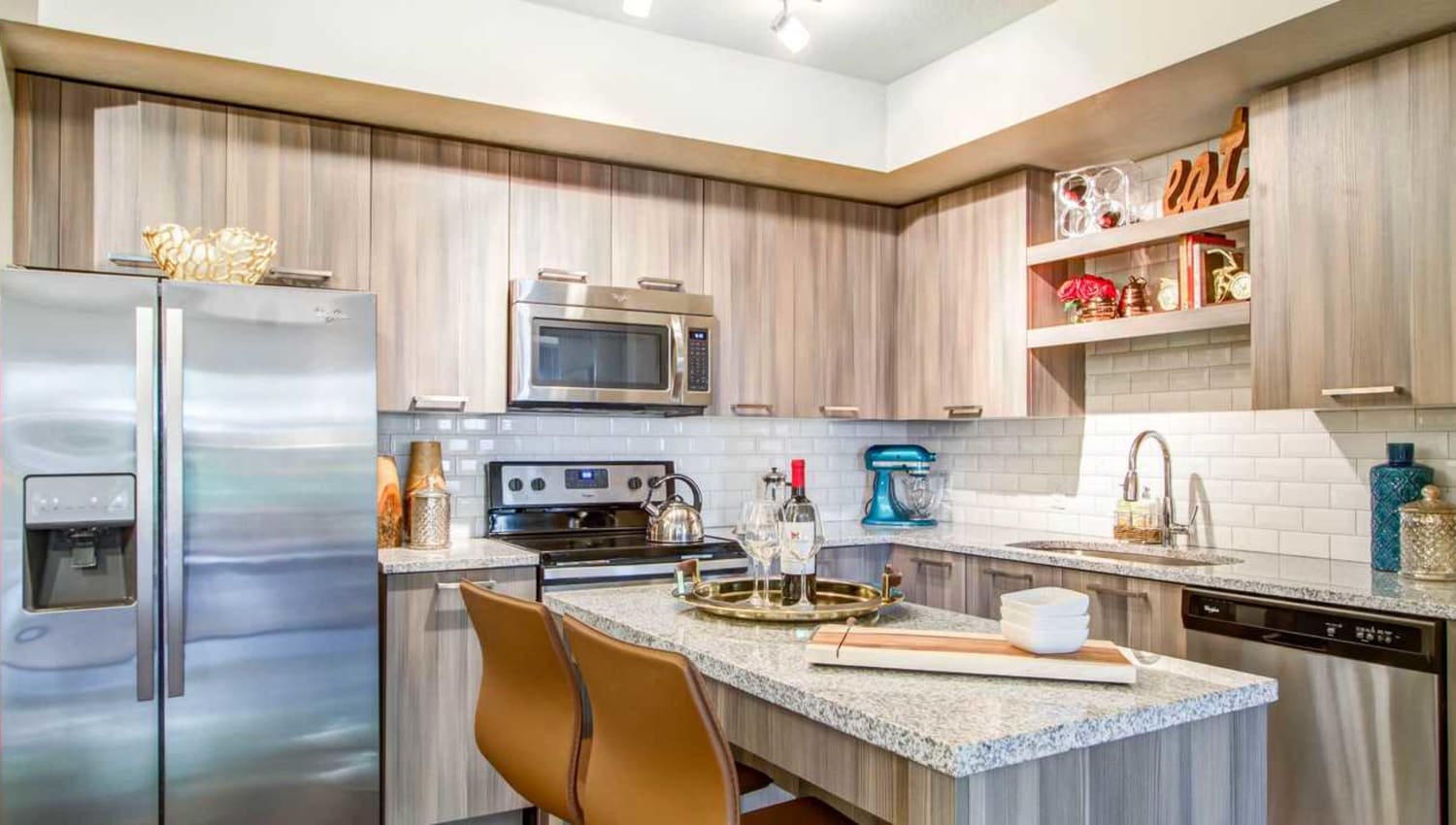 Modern kitchen with granite countertops, glass tile backsplash, and an island at Luzano in Pompano Beach, Florida