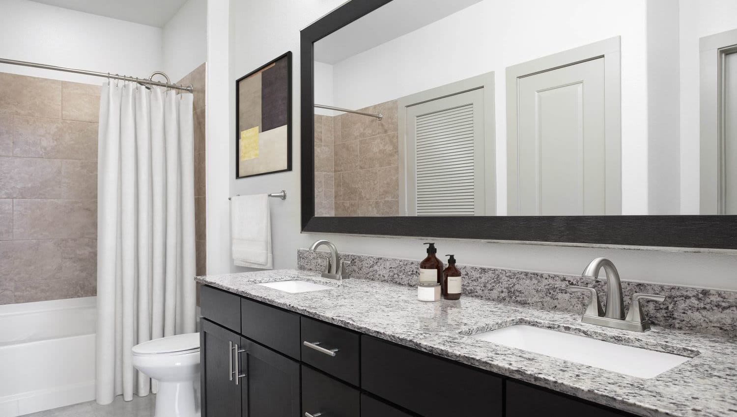 Model bathroom with large vanity mirror at Olympus Falcon Landing in Katy, Texas