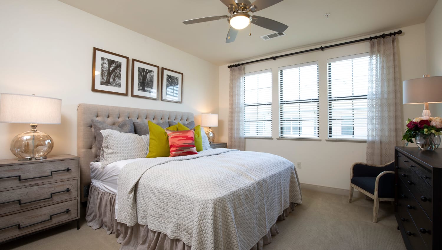 Model bedroom with orange accent pillow at Olympus at Memorial in Houston, Texas