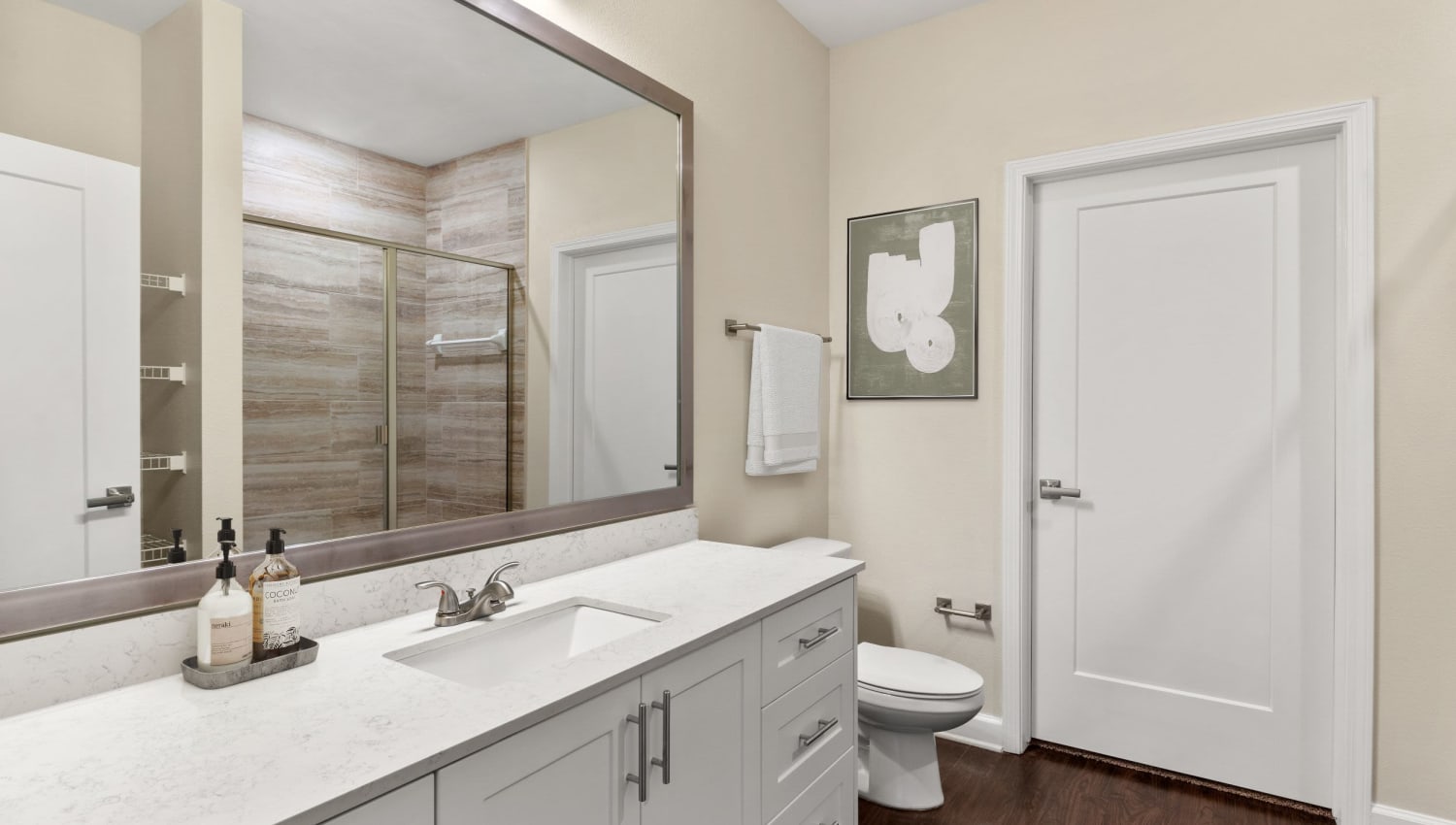 Model bathroom with large vanity mirror and walk in shower at The Point at Town Center in Jacksonville, Florida