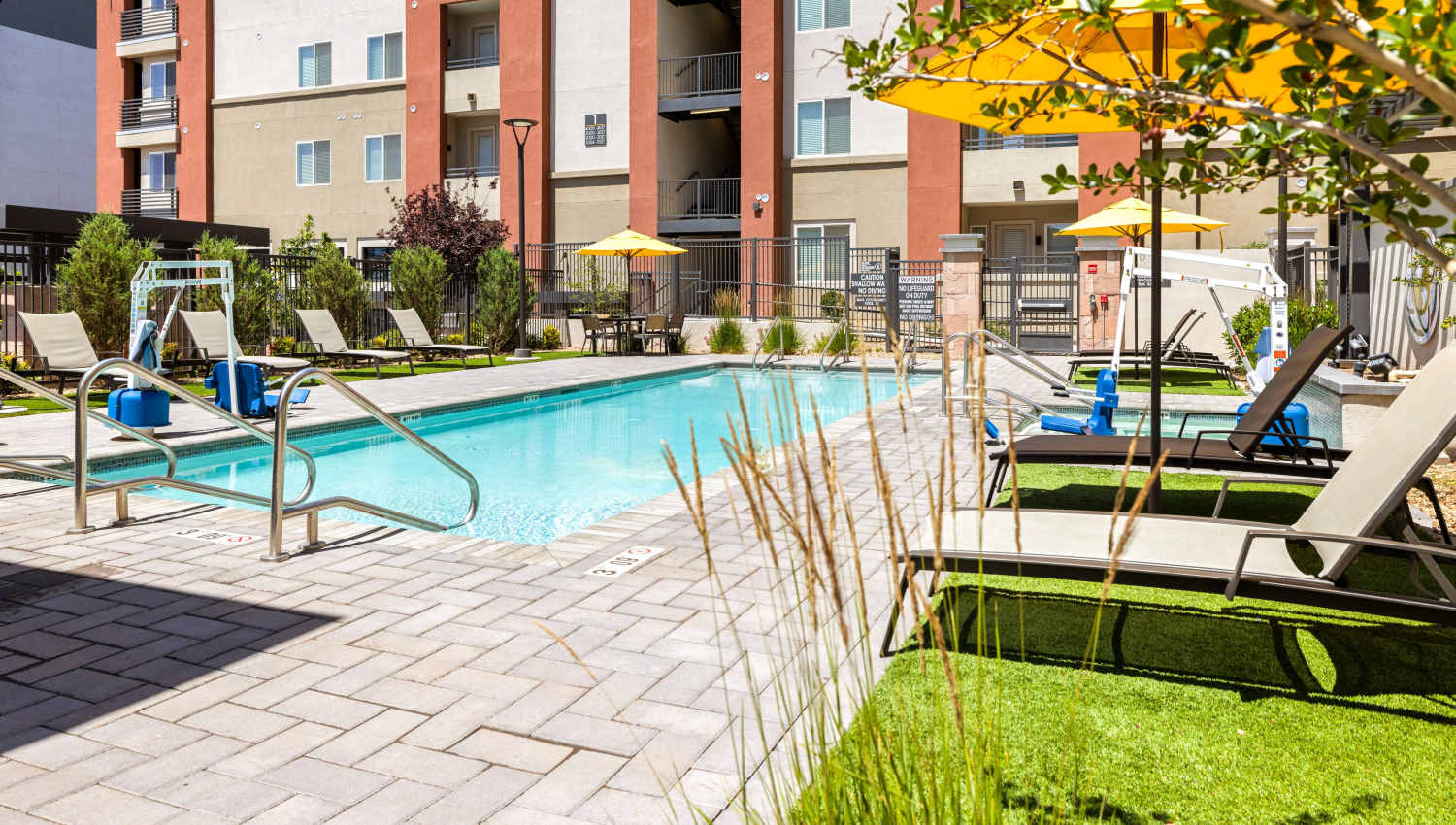 A swimming pool with umbrellas and chairs at Olympus Highlands North in Albuquerque, New Mexico