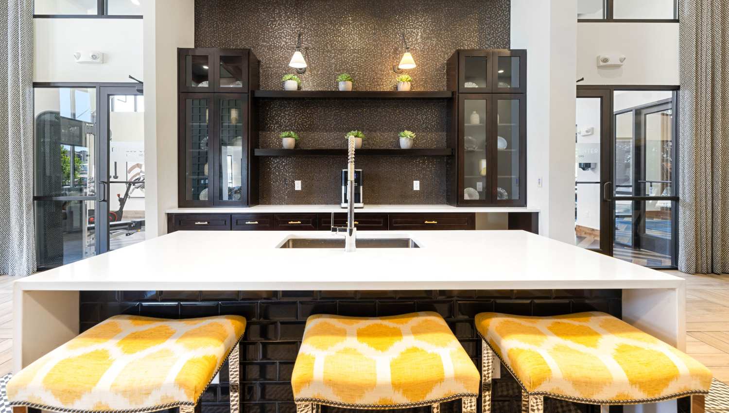 A kitchen with a sink and stools at Olympus Highlands North in Albuquerque, New Mexico