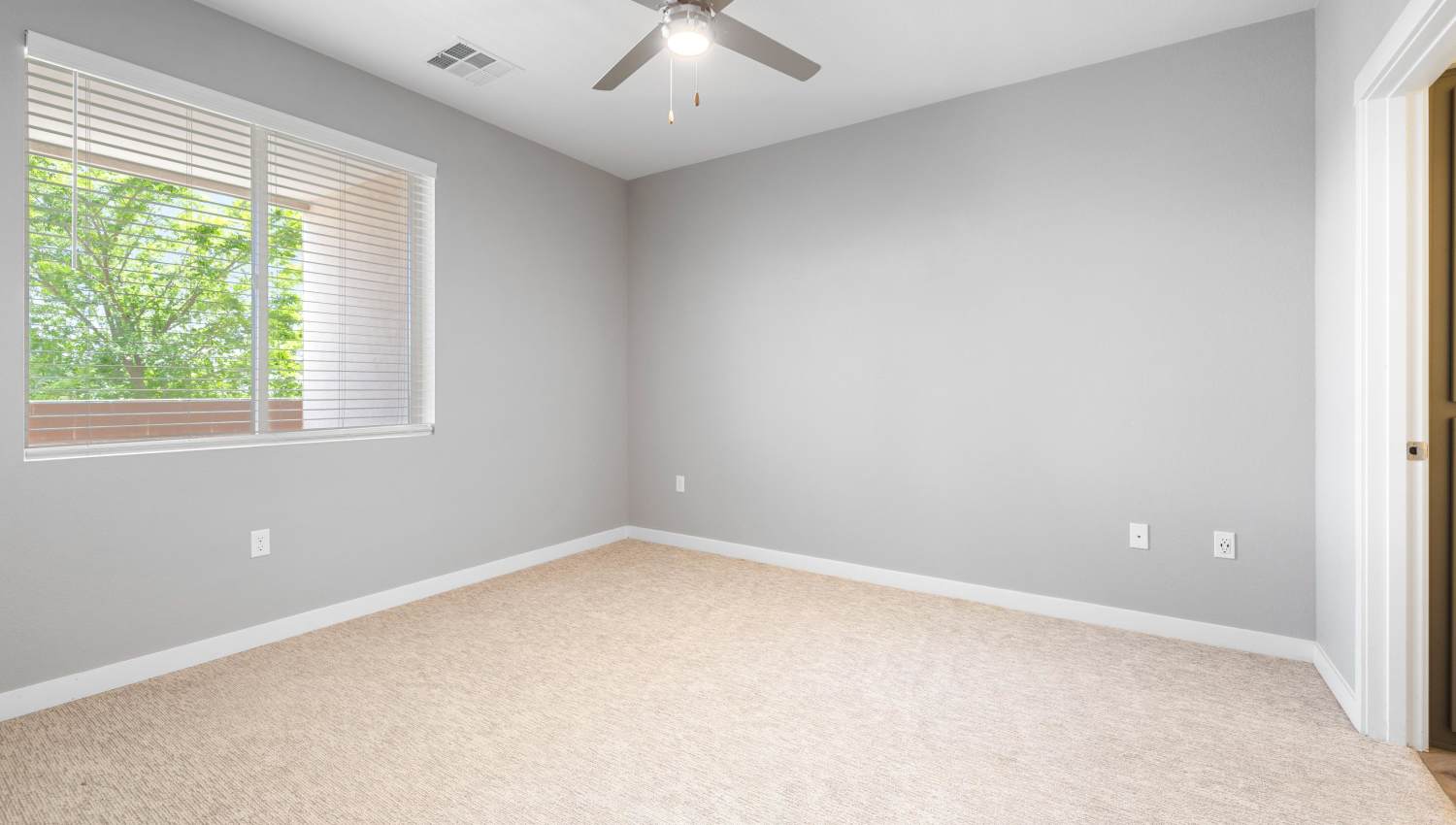 Model bedroom with a ceiling fan and carpet at Olympus Alameda in Albuquerque, New Mexico