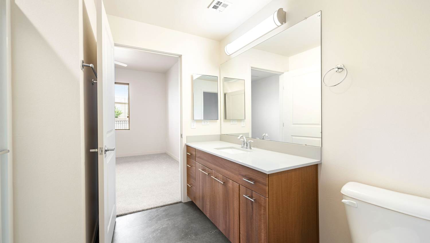 A bathroom with a sink and a toilet with wooden cabinet  at Olympus Alameda in Albuquerque, New Mexico