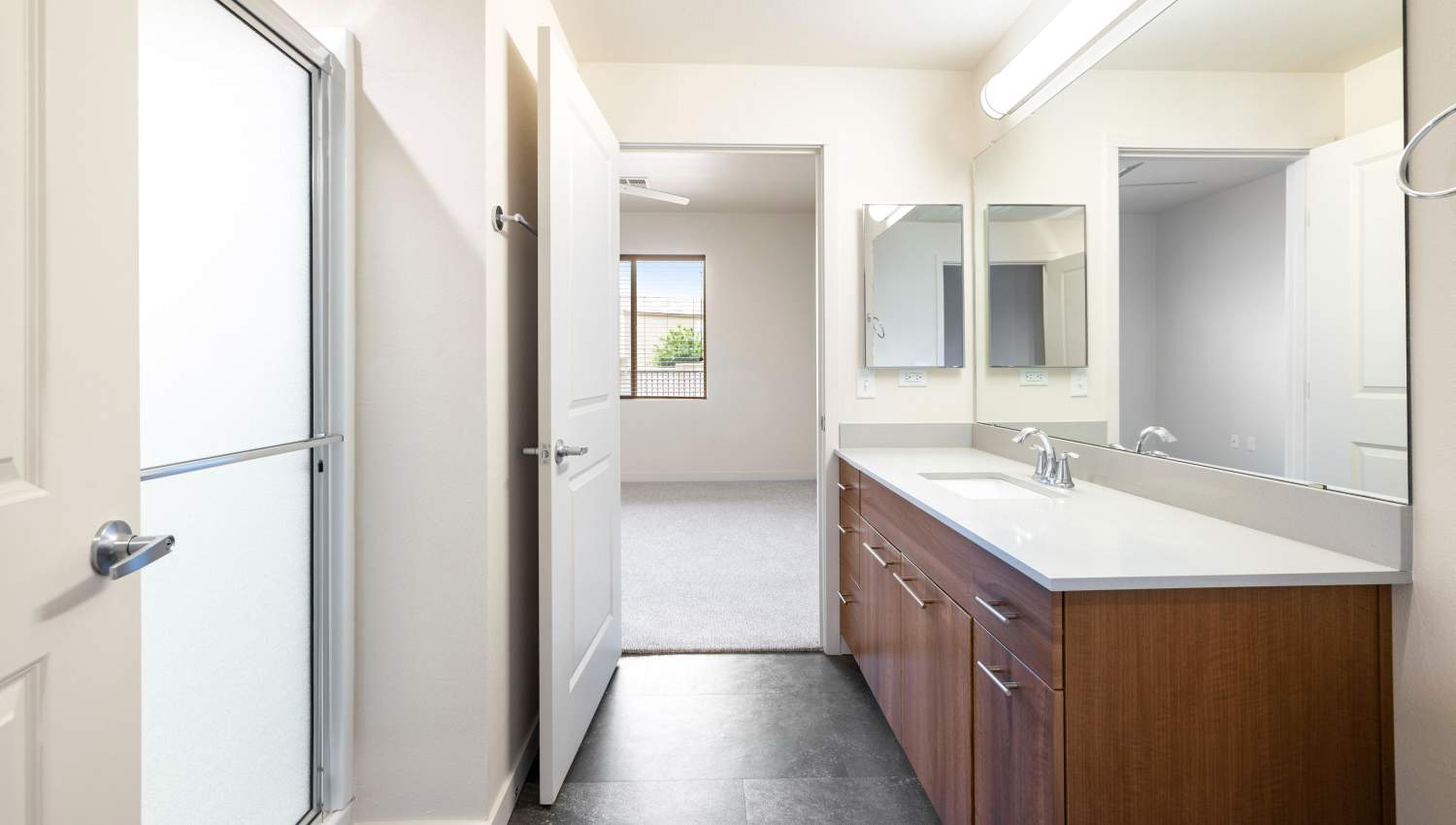 A bathroom with a double sink and two mirrors at Olympus Alameda in Albuquerque, New Mexico