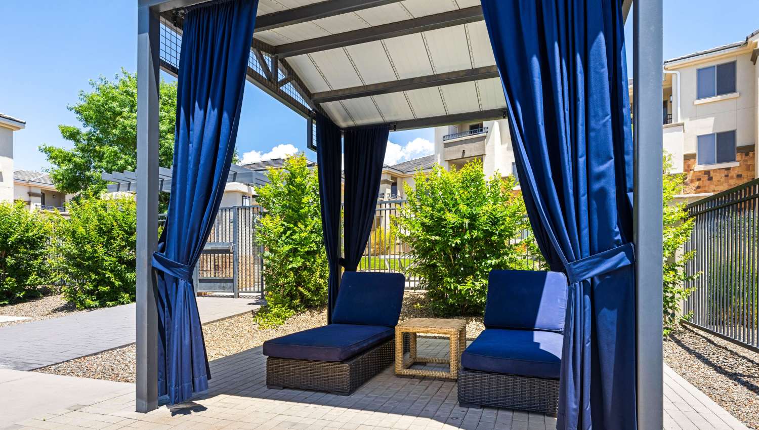 A patio with blue curtains and chairs at Olympus Alameda in Albuquerque, New Mexico