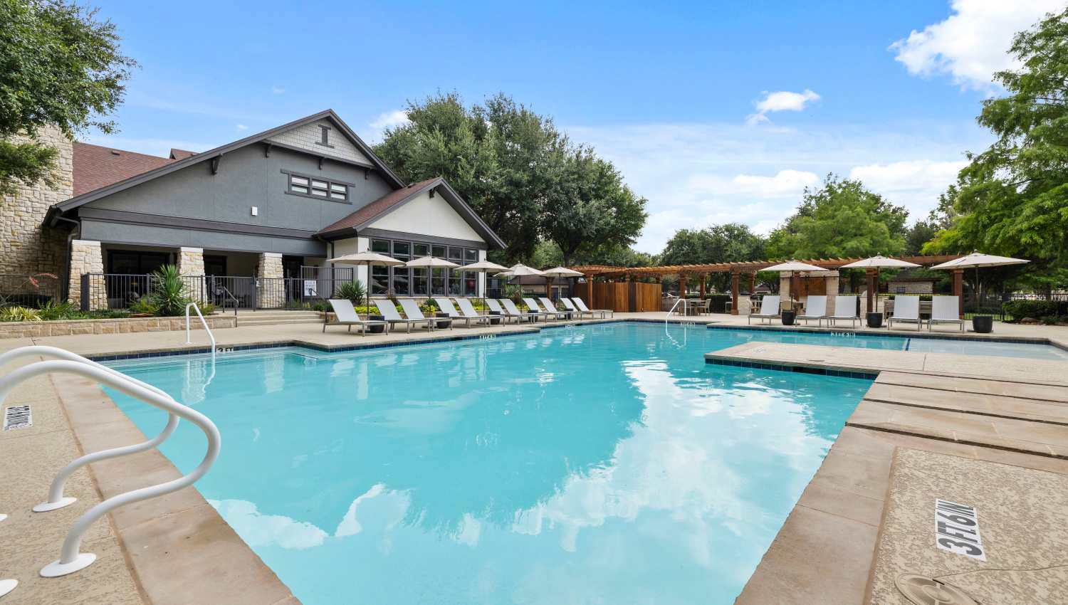 A swimming pool with lounge chairs and a building at Olympus Town Center in Keller, Texas