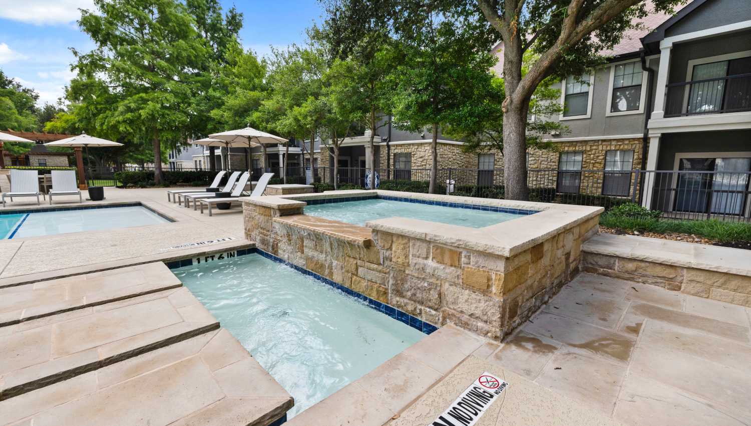A pool with a stone wall at Olympus Town Center in Keller, Texas