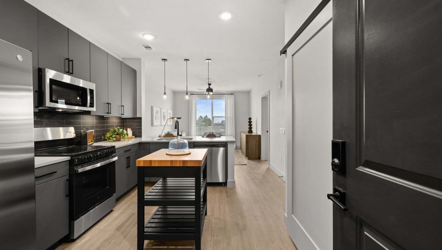 Upgraded kitchen with stainless-steel appliances, hardwood floors and large window at The Lock at Flatirons in Broomfield, Colorado