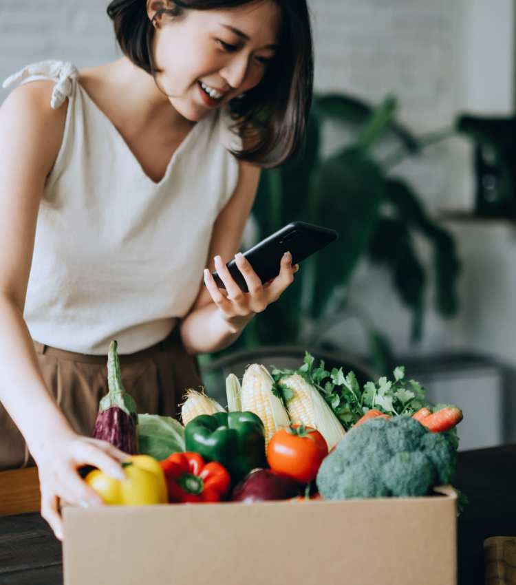 Woman checking her phone and unloading a box of fresh produce at 101 Depot in Smyrna, Tennessee