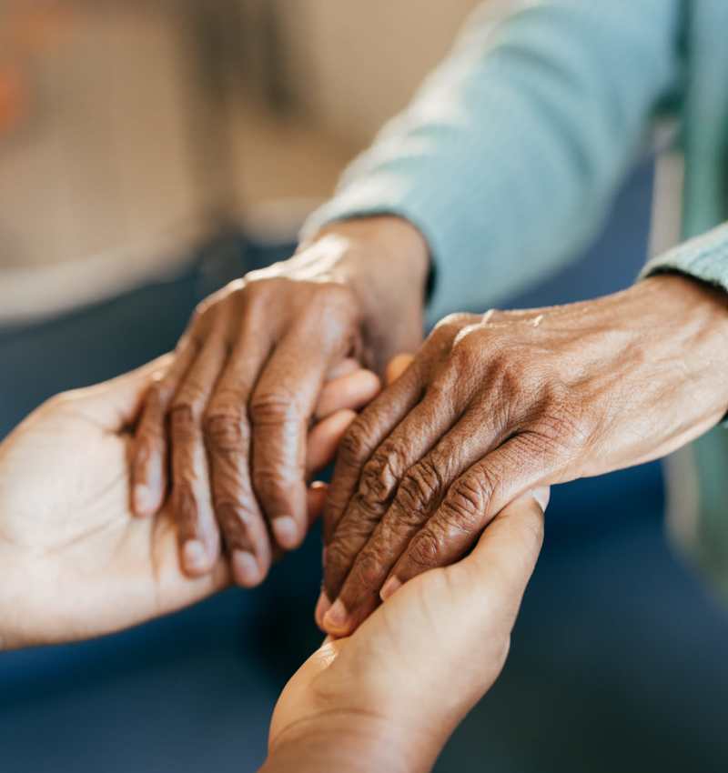 Caretaker holding a resident's hands at Pine Rock Manor in Warner, New Hampshire