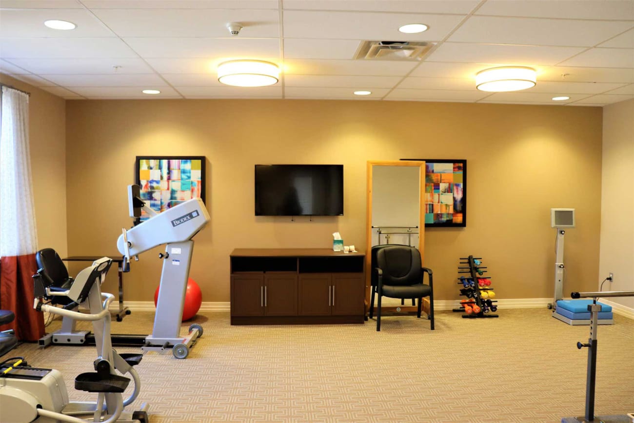 Conditioning equipment and a flatscreen TV in the exercise room at Savanna House in Gilbert, Arizona