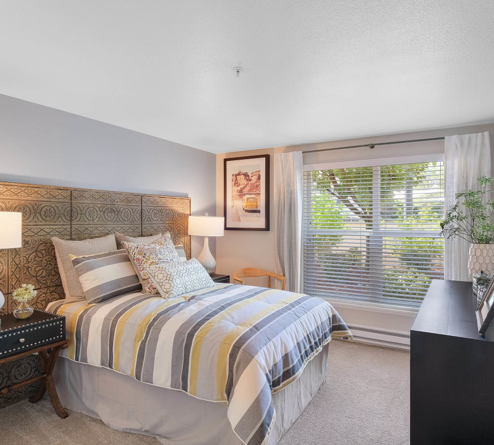 Plush carpeting and a warm, neutral paint scheme in a luxury model home's master bedroom at Centro Apartment Homes in Hillsboro, Oregon