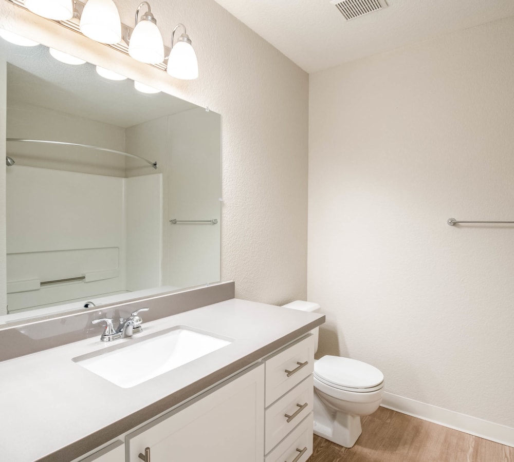 Large bathroom with bright lights and a large Vanity mirror at Shore Park at Riverlake in Sacramento, California