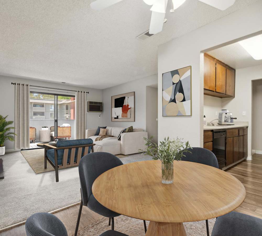 Dining area, kitchen with brown cabinets and black appliances, and living room with sliding door to a patio at Muirwood Apartment Homes in Martinez, California