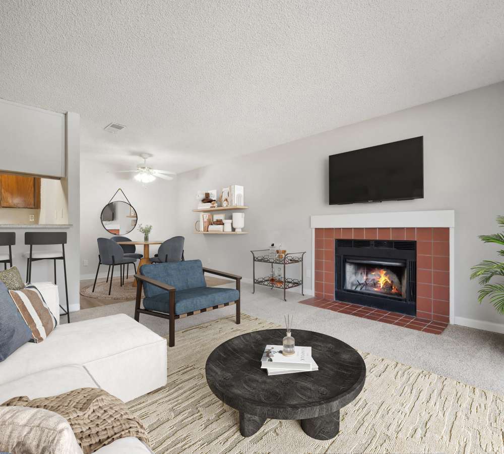 Living room with carpet and fireplace, dining area, and kitchen bar at Muirwood Apartment Homes in Martinez, California