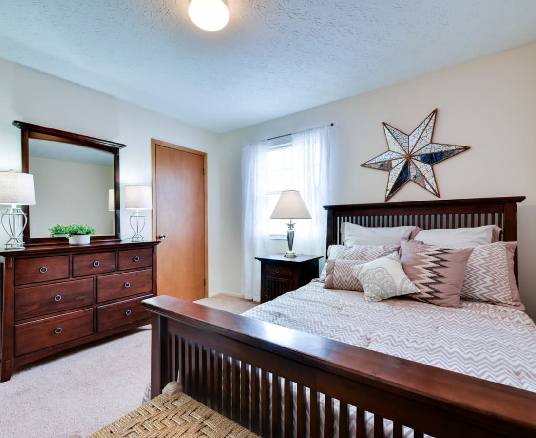 Dark wood furnishings and carpeted floors in a model home's bedroom at Pointe at Northern Woods in Columbus, Ohio