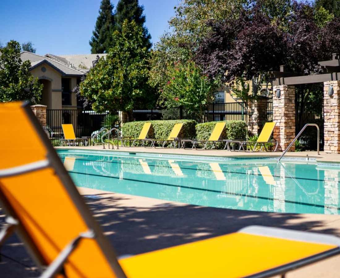 Lounge chairs by the pool at Oak Brook Apartments in Rancho Cordova, California