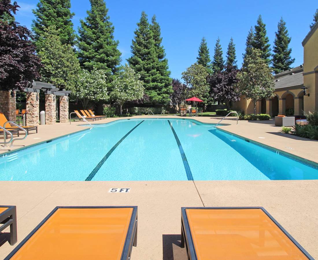 Lounge chairs and pool at Oak Brook Apartments in Rancho Cordova, California