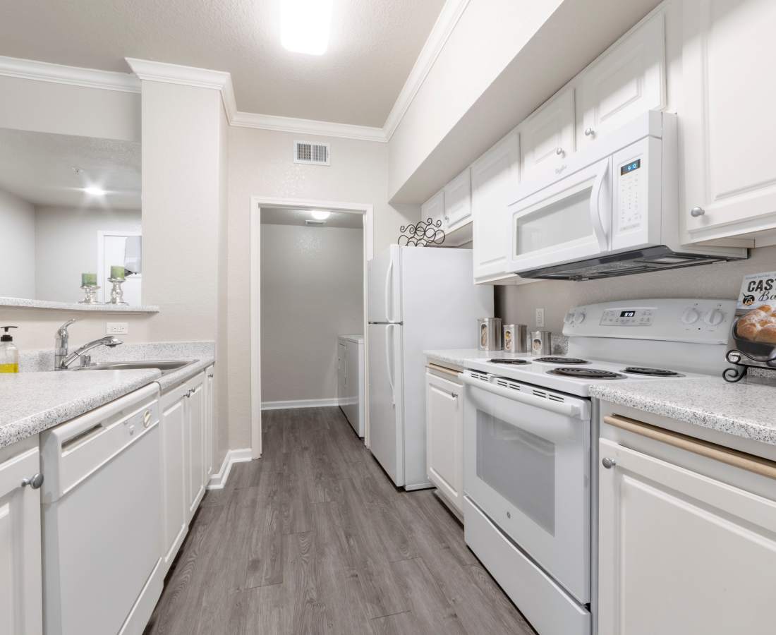 Kitchen with white cabinetry and appliances at Oak Brook Apartments in Rancho Cordova, California