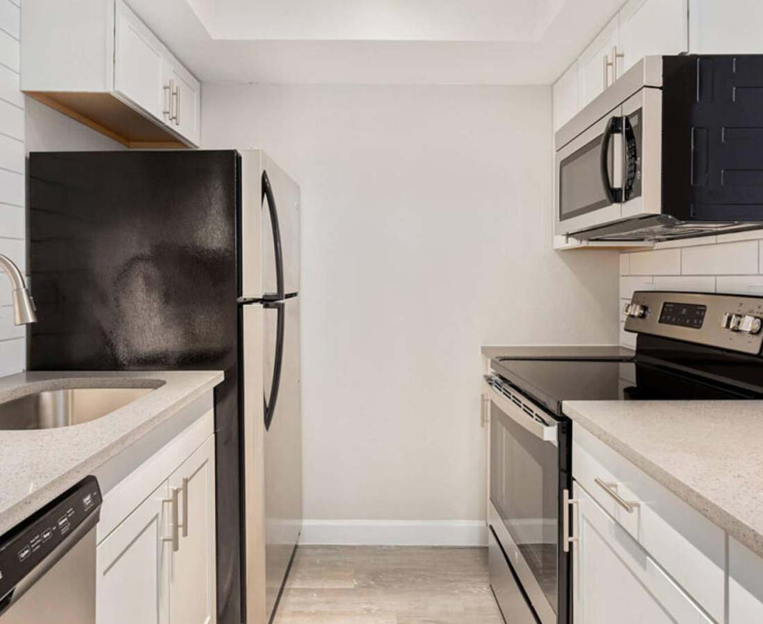 Fully equipped kitchen with granite countertops stainless steel appliances like a refrigerator, stove, and drawer microwave at Raystone Apartments in Phoenix, Arizona