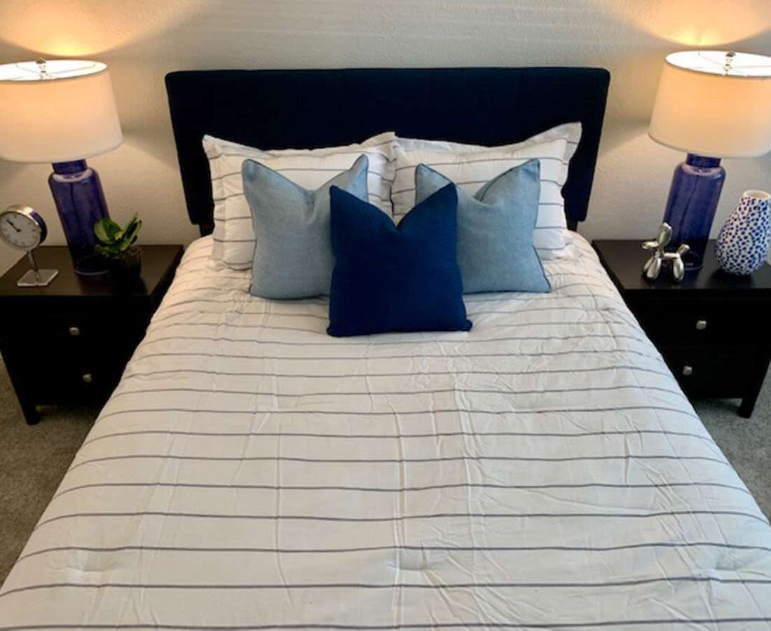 Model apartment bedroom with comfortable bed and bed lamps at 544 Southern Apartments in Mesa, Arizona