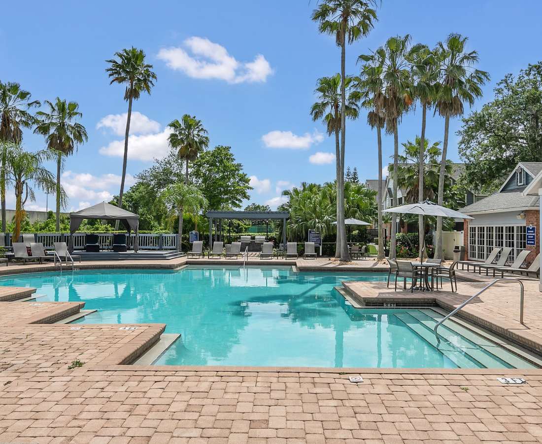 Resort-style swimming pool with multiple lounge chairs and surrounded by trees at Rosemont Windermere in Orlando, Florida