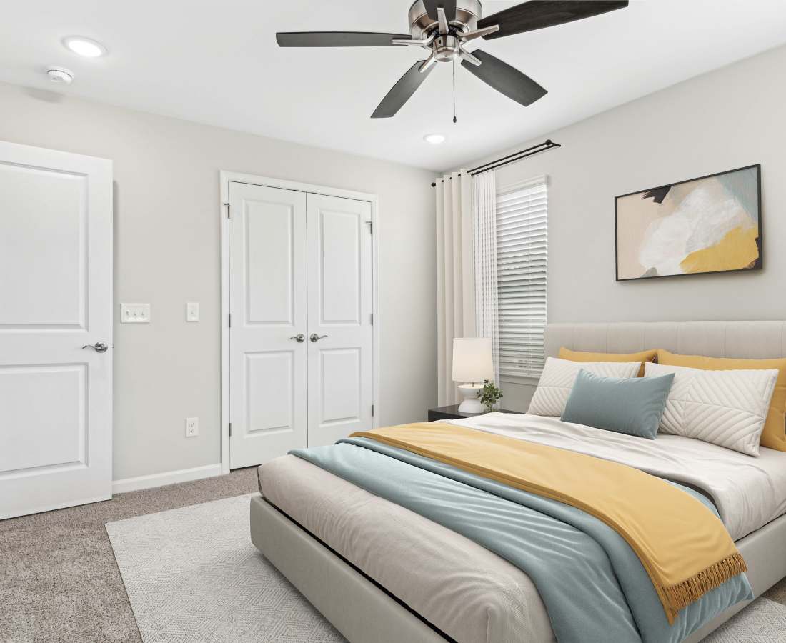 Bright bedroom with ceiling fan and closet space at Westmont Village in Charlotte, North Carolina