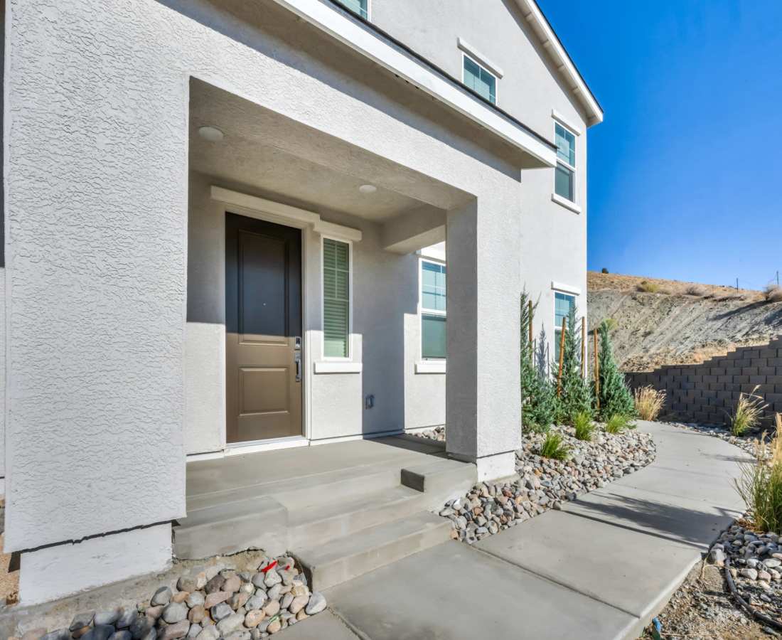 A home featuring a stone walkway leading to a large rock wall, surrounded by greenery at Prosper 83 in Sparks, Nevada