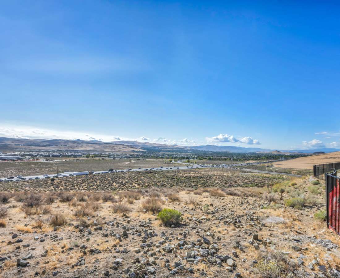 A scenic view of distant mountains with a wooden fence in the foreground at Prosper 83 in Sparks, Nevada